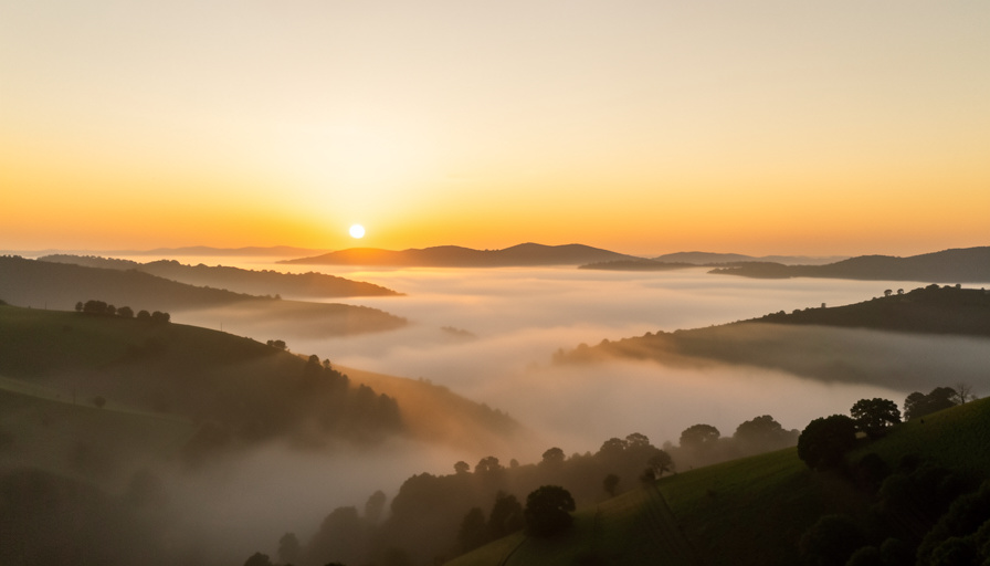 A warm sunrise glowing over calm misty hills at dawn, suggesting the natural morning rise of cortisol in the body's daily rhythm