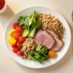 A colorful balanced plate of fresh healthy food with vegetables, whole grains, and lean protein on a clean table in warm light