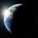 Planet Earth seen from space, half lit by the Sun and half in shadow with a clear day-night line, tilted slightly against a field of stars