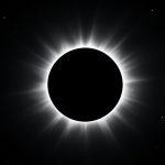 A total solar eclipse with the black disk of the Moon covering the Sun and the glowing white corona spreading out against a dark sky